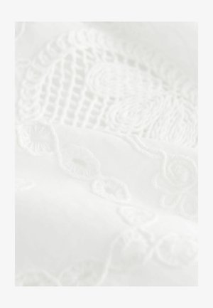 Bijela tkanina s složenim podignutim vezenim motivima cvijeća i zavojitih uzoraka, koja prikazuje blagu teksturu i glatku završnu obradu.