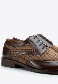 Chaussures en cuir marron avec des accents à motif tissé, présentant un bout arrondi, un laçage et une finition lisse et polie.