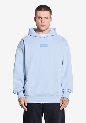 Jasnoniebieska bluza z kapturem, wykonana z miękkiego materiału, z kieszenią z przodu i naszywką z logo na klatce piersiowej. Luźny krój z ściągaczami przy mankietach.