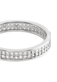 Anneau en argent avec une bande lisse et une rangée de petites pierres rondes et claires serties dans un canal sur un côté, présentant une finition polie.