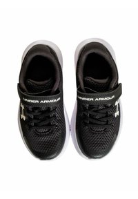 Zapatillas deportivas negras con parte superior de malla, suela blanca y correa ajustable. Presentan cordones y la marca "Under Armour".