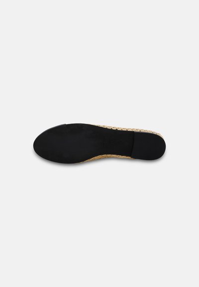 Semelle plate de chaussure avec fond noir lisse et bord supérieur beige tissé, présentée sur un fond clair uni.