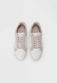 Calvin Klein sneakers met een witte leren basis, beige suède accenten en bijpassende veters. Rond neus en gevoerde stoffen voering.