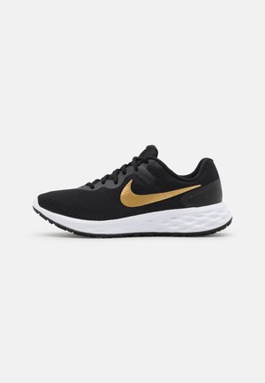 Zapatilla de correr negra con suela blanca y símbolo Nike dorado, mostrando el perfil lateral sobre un fondo liso gris claro.