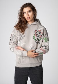 Grijze hoodie met diverse graphics, waaronder een bloem, tekst en abstracte ontwerpen. Zachte textuur met ribgebreide boorden en een zoom.