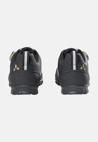 Schwarze Sportschuhe mit strukturierter Oberseite aus Stoff, geriffelter Gummisohle, reflektierenden Details und kontrastierenden metallischen Akzenten an der Ferse.