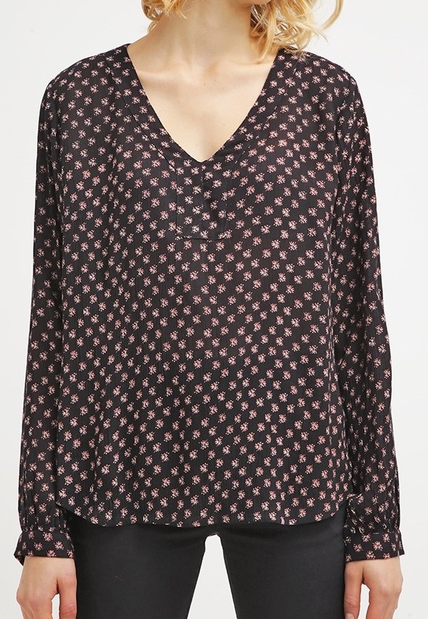 Blouse noire à manches longues avec un décolleté en V profond, présentant un petit motif floral rose. Fabriquée en tissu léger et semi-transparent.