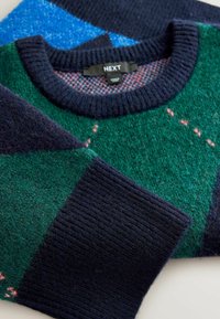 Sweter z dzianiny w zielone, niebieskie i granatowe wzory. Posiada prążkowany dekolt i mankiety. Miękka faktura z warstwowym designem. Widoczna metka marki.
