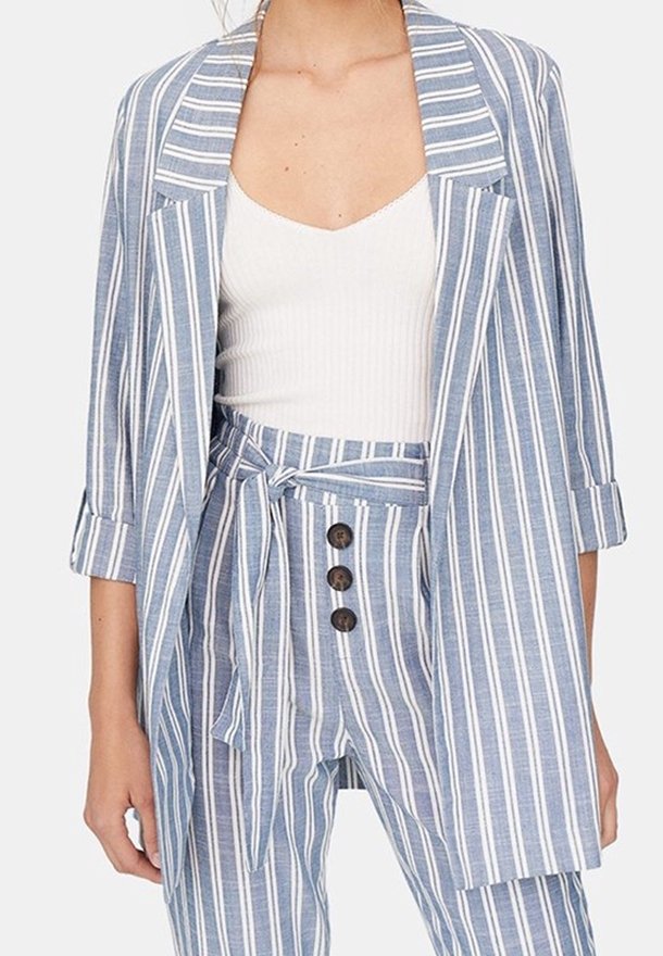 Pasiasty niebiesko-biały żakiet z długimi rękawami, zestawiony ze spodniami w kolorze dopasowanym o wysokim stanie z zapięciem na sznur i guzik.