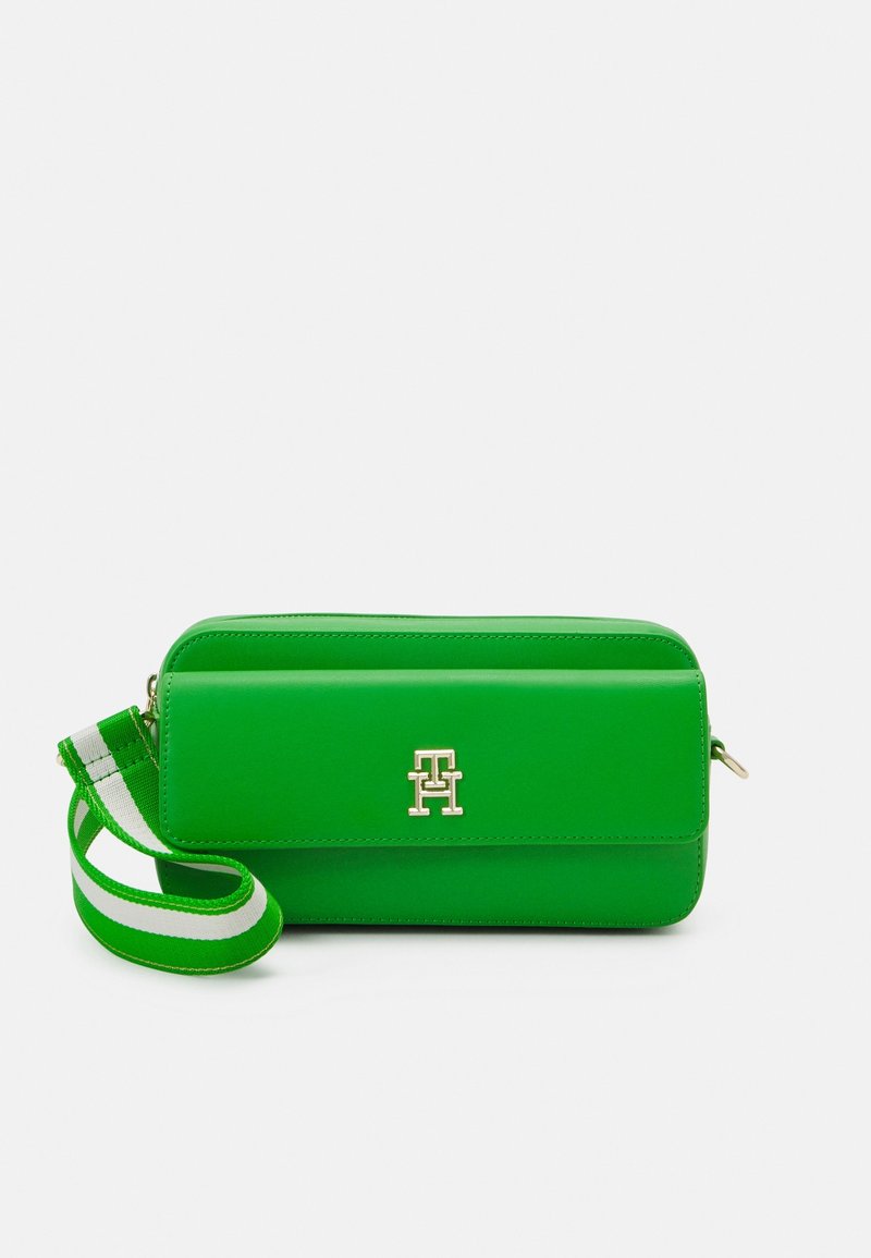 Zelená kabelka přes rameno z faux kůže se zlatým logem, zipovým uzávěrem a nastavitelným pruhem zelené a bílé barvy.