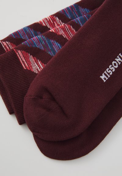 Bordeauxfarbene und mehrfarbige gemusterte Socken aus weichem Strickmaterial, wobei eine Socke die Marke "M MISSONI" in Weiß zeigt.