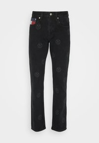 Black denim jeans with a straight cut, featuring embossed smiley face patterns and a patch with red, white, and blue colors on the pocket.