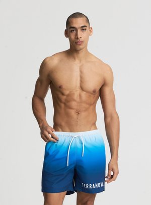 Uomo muscoloso con capelli corti che indossa pantaloncini da bagno blu sfumato con coulisse bianca e logo "TERRANOVA" sulla gamba sinistra.