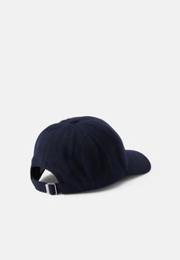 Navy blue baseball cap made of textured fabric, featuring a curved visor and adjustable strap at the back. Seam details visible.