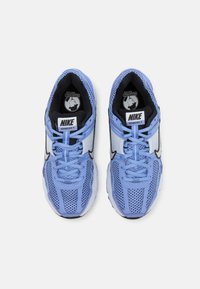As sapatilhas Nike Vomero 5, em azul-claro, apresentam um upper em malha, detalhes em preto, língua acolchoada e o logo da Nike em branco nas laterais.