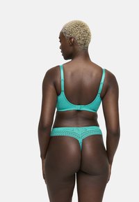 Turquoise kant lingerie set met een bralette met verstelbare bandjes en bijpassende string. Fijne patronen sieren de stof.