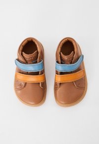 Braune Lederschuhe mit zwei Klettverschlüssen, einem orange und einem blauen, abgerundetem Zehenbereich und brauner Gummisohle. Glatte Textur.