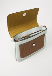 Gaiši zila ādas soma ar brūnu austas priekšējā kabatu. Atvērta flapa atklāj zelta iekštelpu un rāvējslēdzēja nodalījumu. Sudraba aparatūra.