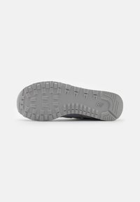 Gray athletic shoe sole with textured tread, featuring deep grooves for traction and a slight curve at the toe for improved flexibility.