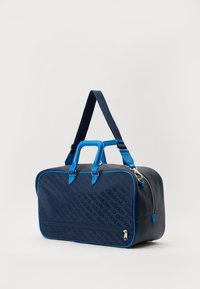 Saco de viagem da Marinha com detalhes em azul, feito de material liso. Possui alças, uma correia de ombro e um compartimento com fecho. Detalhe do logótipo em padrão.