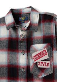 Camisa de cuadros roja, negra y azul con botones, que cuenta con un bolsillo en el pecho que presenta parches blancos que dicen "ROCKER" y "STYLE". Textura de tela suave.