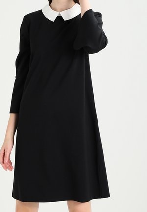 Vestido negro con cuello blanco, mangas tres cuartos, corte en línea A y textura suave. Presenta un diseño sencillo con detalles mínimos.