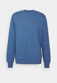 Sudadera azul de mezcla de algodón, con un cuello redondo, puños acanalados y un pequeño logo rojo en el pecho. Textura suave.
