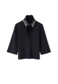 Zwarte top met driekwart mouwen, een hoge hals, een gestrikt strikje, en een zwarte kraag versierd met zilveren bloemenmotieven.