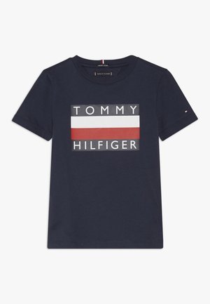 Navyblaues Baumwoll-T-Shirt mit einem großen Grafiklogo, das den Text "TOMMY" und "HILFIGER" zeigt, akzentuiert durch ein rotes und weißes rechteckiges Streifenmuster.