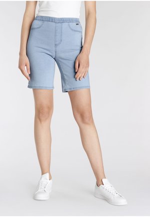 Hellblaue Denim-Bermudas mit einem elastischen Bund, zwei vorderen Taschen und einem knielangen Schnitt, kombiniert mit weißen Sneakern.
