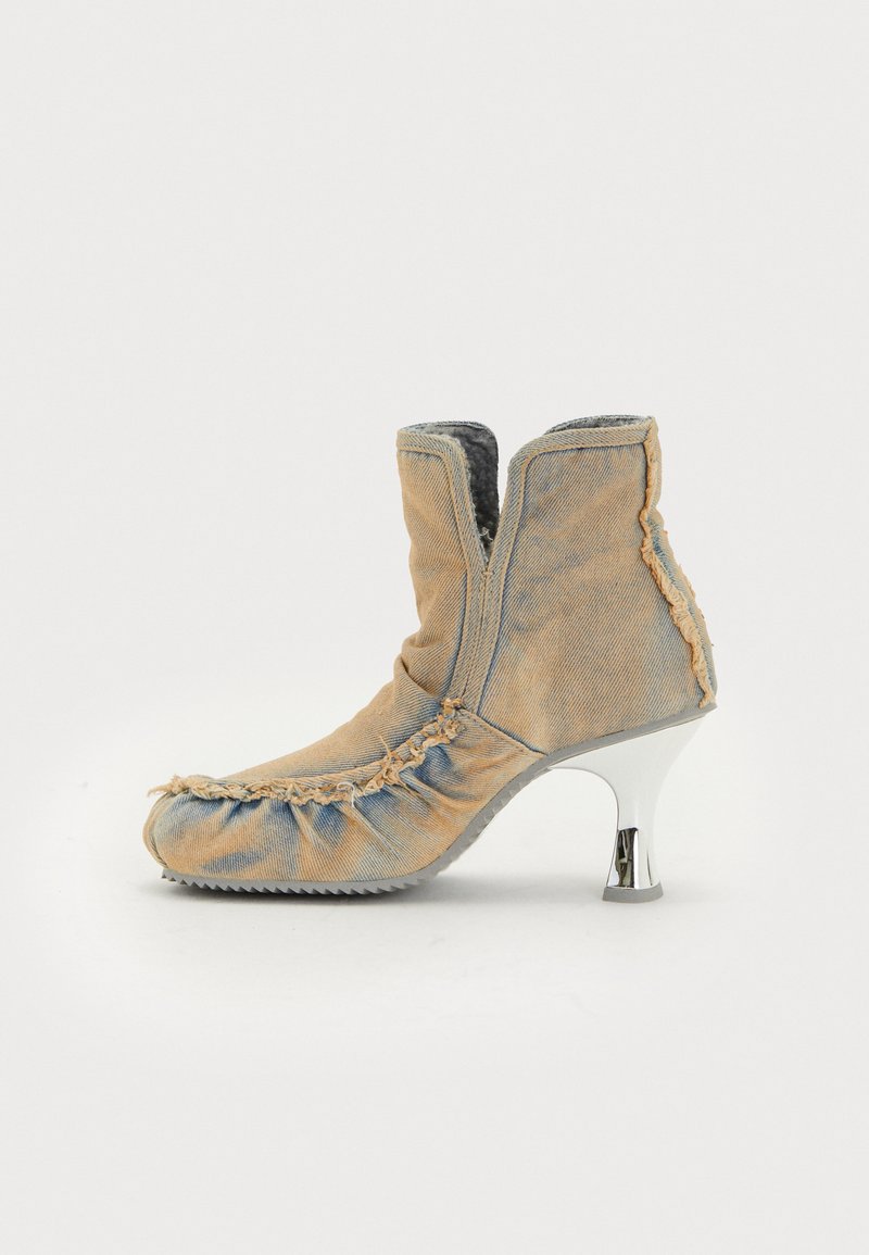 Denim-Ankelstiefel mit gerüschter Textur, beiger Farbe, silbernem Stiletto-Absatz und sichtbaren Nähdetails. Seitlicher Reißverschluss zum Schließen.