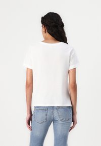 Hvid kortærmet t-shirt lavet af blødt stof, med en klassisk rund halsudskæring og en afslappet pasform. Sættes sammen med blå skinny jeans.