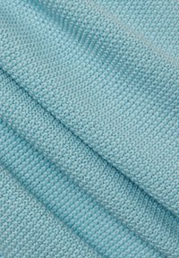 Helleblaue gestrickte Stoff mit feiner Textur, der Reihen von Stichen und sanften Falten zeigt und seine Weichheit und Dehnbarkeit betont.