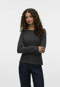 Zwart-wit gestreept shirt met lange mouwen en een bootnek, zachte textuur en een relaxed fit, gecombineerd met donkerblauwe spijkerbroek.