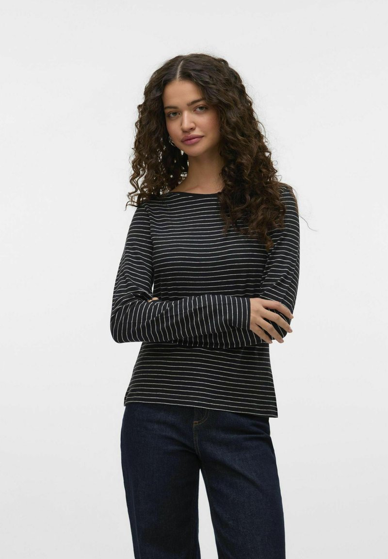 Zwart-wit gestreept shirt met lange mouwen en een bootnek, zachte textuur en een relaxed fit, gecombineerd met donkerblauwe spijkerbroek.