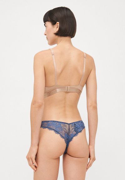 Beha met subtiele beige banden en een haaksluiting. Blauw kanten slipje met bloemenpatroon en semi-doorzichtige stof.