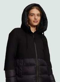 Zwarte hoodiejack met een gladde, gestructureerde stof aan de bovenkant en een gewatteerde, dikke onderkant. Voorzien van trekkoorden en een ritssluiting aan de voorkant.