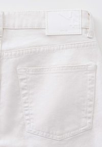 I jeans in denim bianco presentano una tasca posteriore, un'etichetta rettangolare bianca in vita e cuciture visibili. La texture appare liscia e robusta.