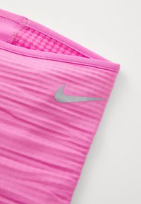 Rosa Sportoberteil mit einem strukturierten Streifenmuster, ausgestattet mit einem grauen Nike-Swoosh-Logo an der Seite und einem glatten, elastischen Stoff.