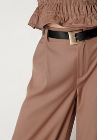 Brązowe spodnie typu wide-leg wykonane z gładkiego materiału, z przednimi kieszeniami i czarnym paskiem z złotą klamrą.