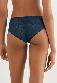 Marineblauwe kantonderbroek met een bloemenpatroon, scalloped randen en een zachte, gestructureerde afwerking, ontworpen voor een comfortabele pasvorm.