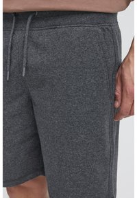 Pantaloncini grigi in cotone con cintura elastica e coulisse, dotati di tasche laterali e una texture liscia.