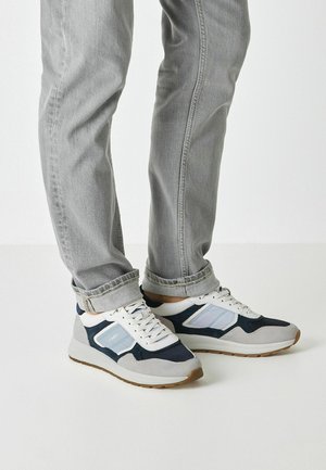 Herren-Sportschuhe mit einer Mischung aus Marineblau, Hellgrau und Weiß; mit Wildleder- und Mesh-Texturen, abgerundeter Spitze und flacher Sohle.