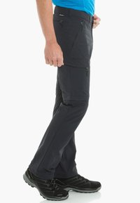 Pantalones exteriores en color navy con bolsillos con cremallera, corte recto y tejido ligero. Combinados con zapatos de senderismo negros.