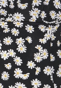 Svart tyg med blommönster av vita och gula prästkragar, med lätta veck och textur synliga.