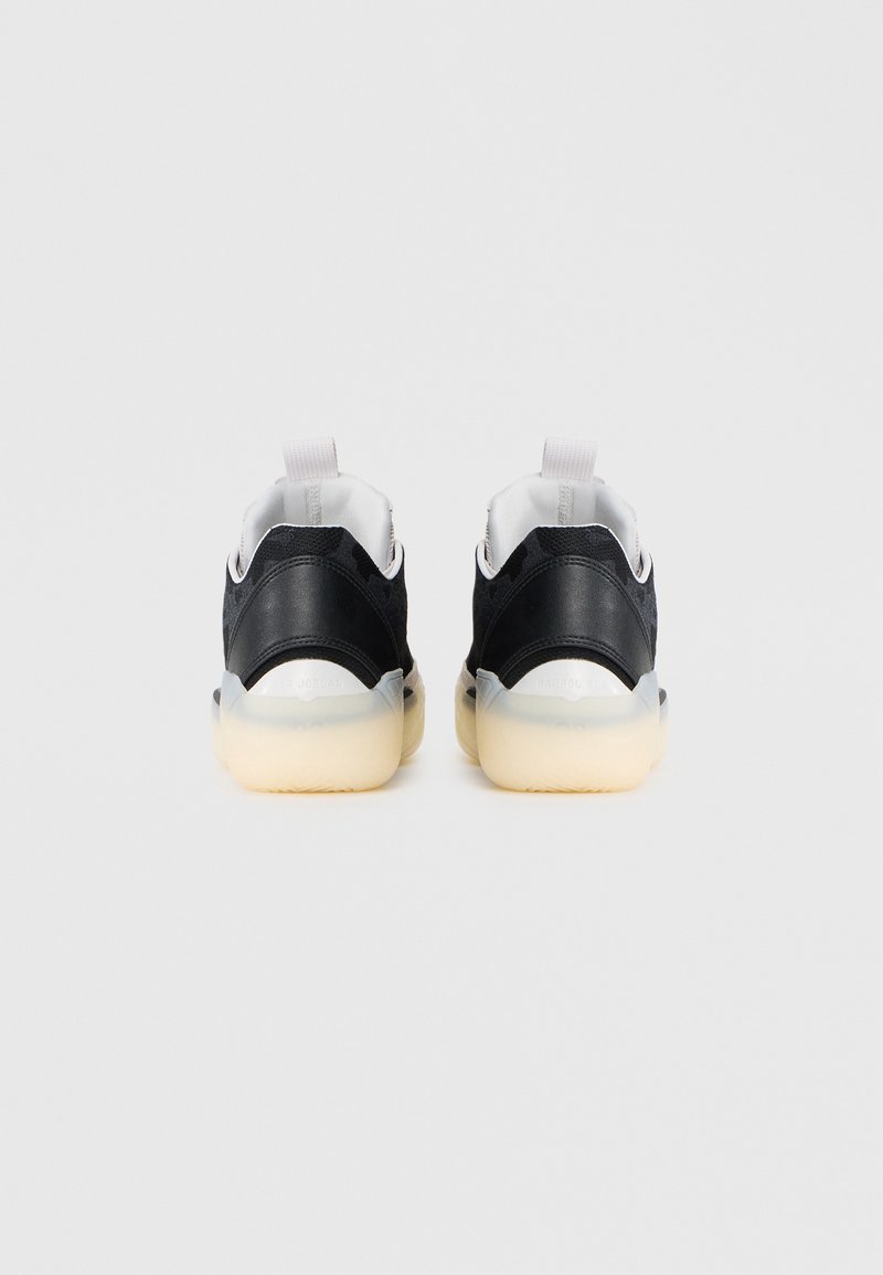 Zapatillas deportivas negras con parte superior texturizada, detalles en blanco y suela de goma translúcida. Cuenta con una lengüeta trasera para facilitar su puesta.