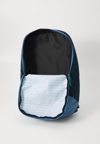 Rugzak in marineblauw met lichtblauwe accenten. De binnenkant heeft een lichtblauwe, gemêleerde voering en een zwarte stoffen voering bij de opening.