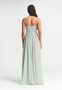 Maxi suknelė iš minkštos mėtų žalumos medžiagos, turinti smockinį liemenį, plonus petnešas ir tekančią sijoną. Lygus audinys ir lengvas dizainas.