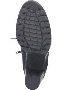 Suela de goma negra con relieve texturizado, con un ligero tacón y un zipper lateral. La parte superior presenta un diseño cosido con suaves curvas.