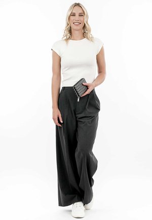 White fitted t-shirt, high-waisted gray wide-leg pants, holding a black patterned clutch. White sneakers complete the outfit.